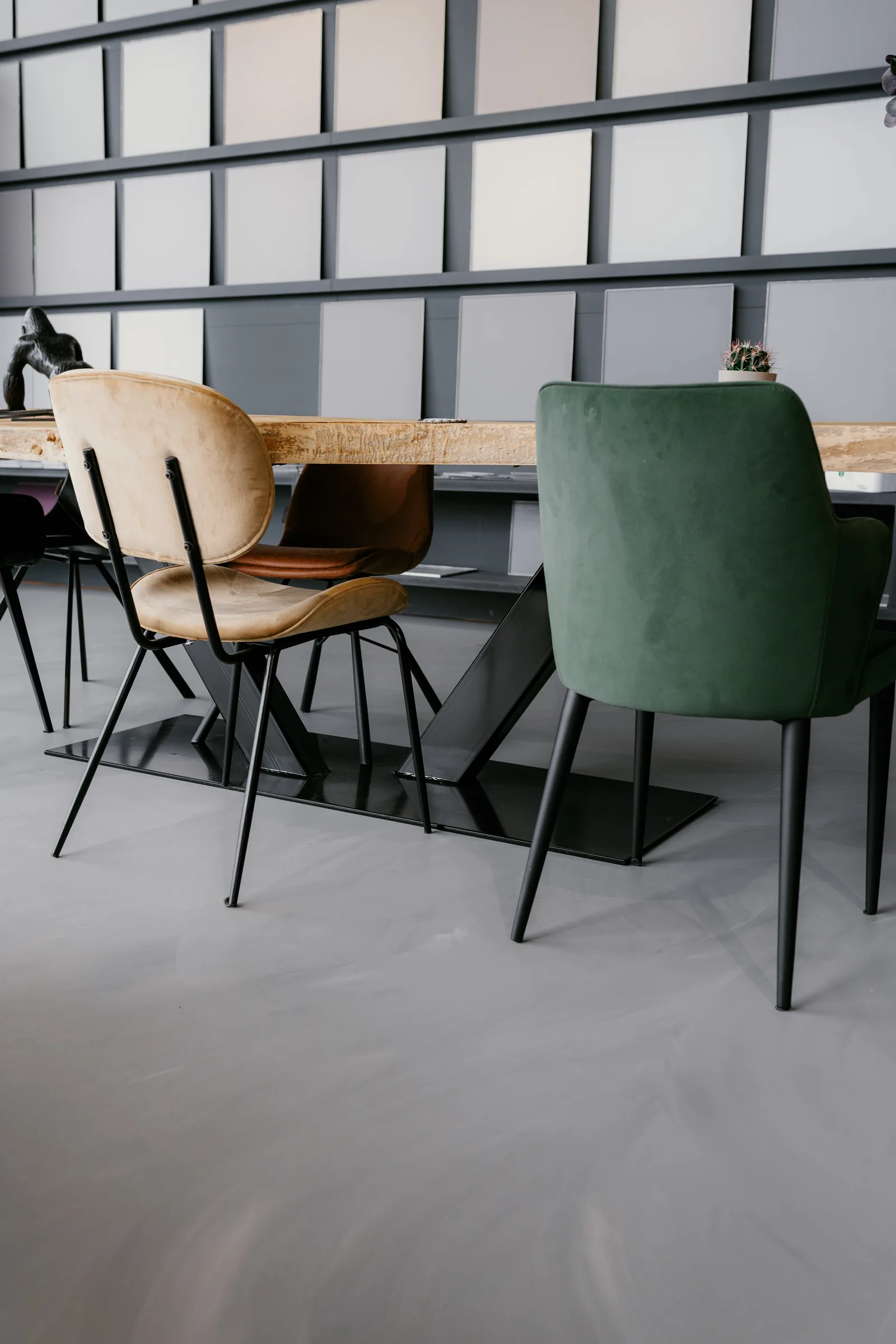 Concrete-look resin floor in a showroom with a wall of colour samples and velvet chairs