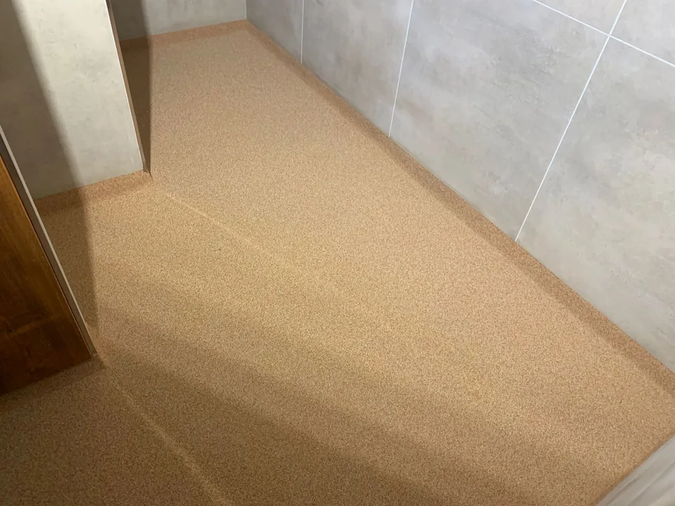 Beige quartz floor with an upstand against a grey tiled wall