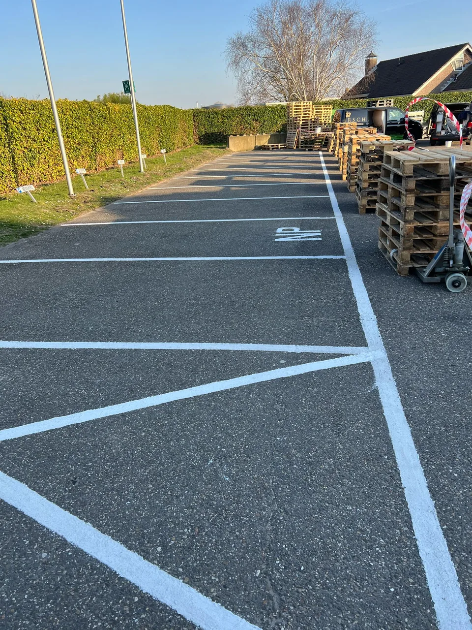 Slip-resistant parking coating with white bay lines on an outdoor area next to a warehouse
