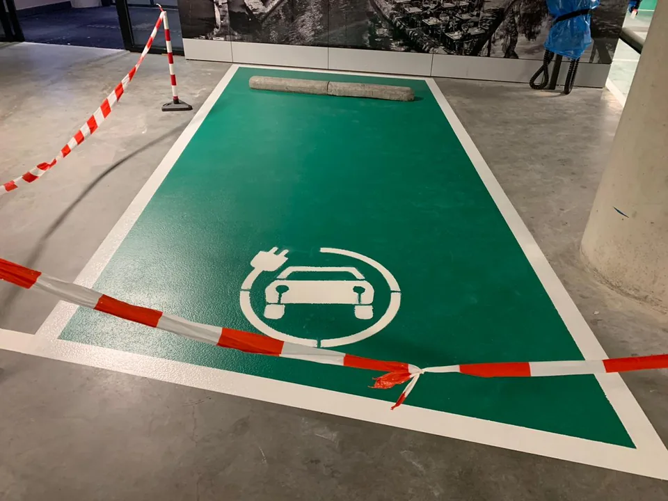 Green Comforpark parking bays for electric charging with white lines and a charging symbol in a car park