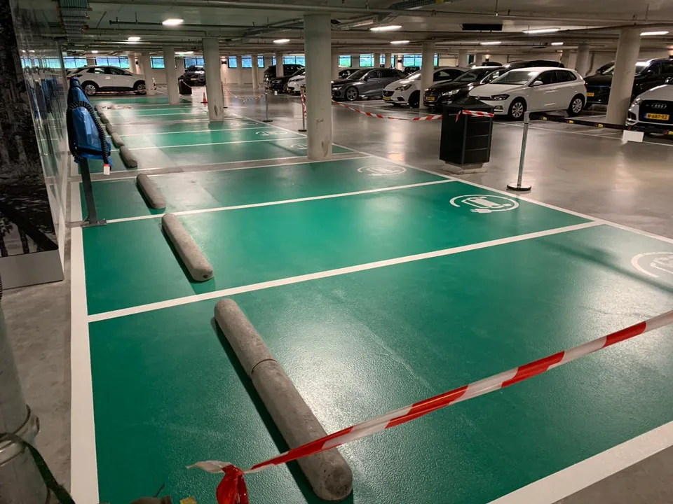 Green-coated charging bays with white markings in an underground car park