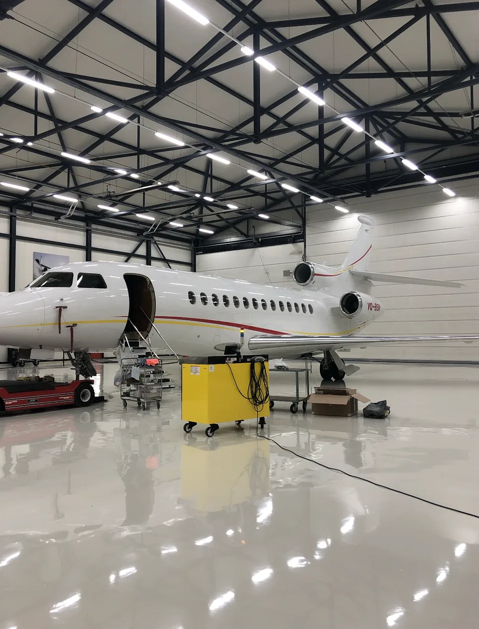 High-gloss epoxy resin floor in an aircraft hangar with a business jet and maintenance equipment