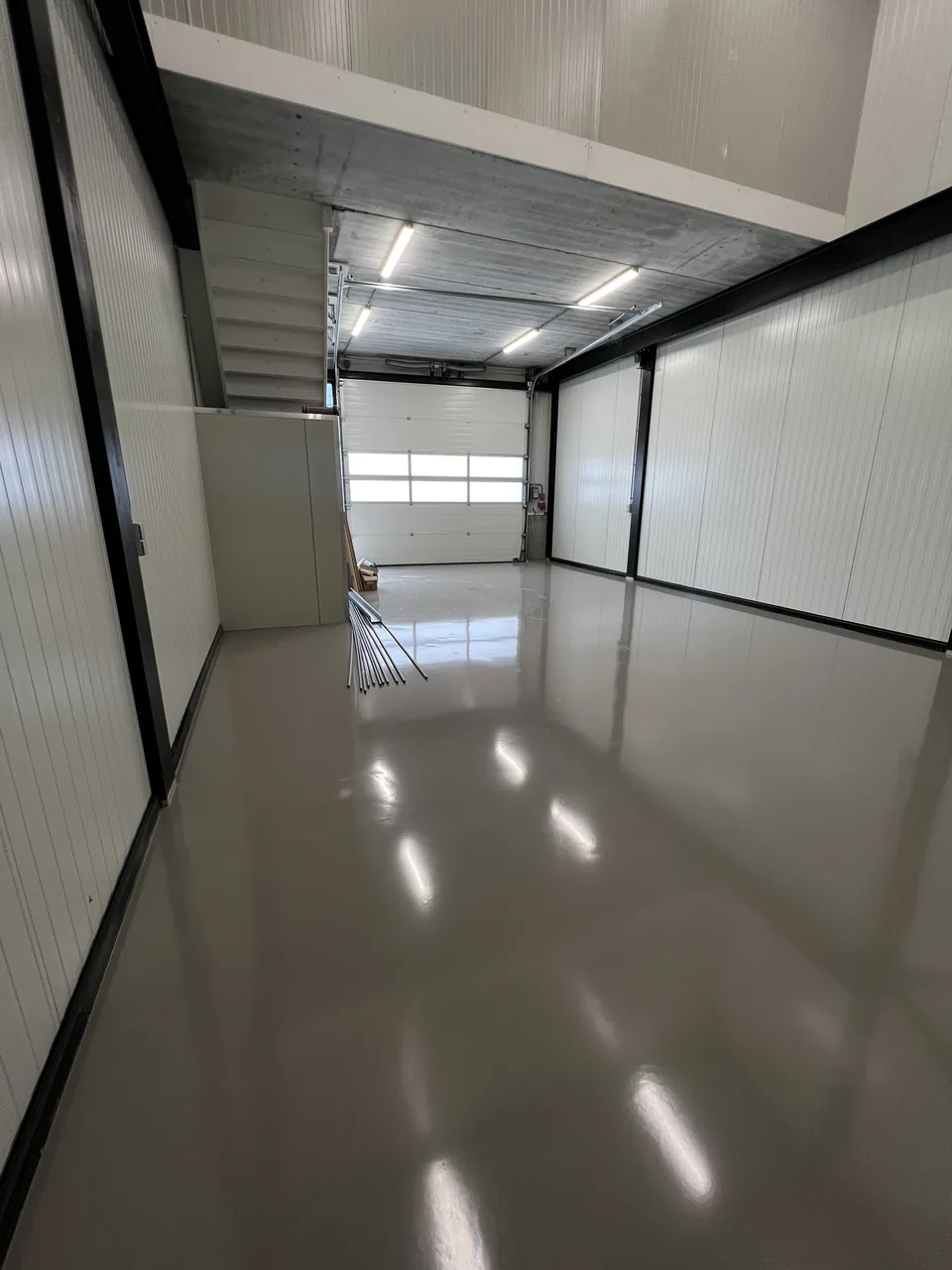 Reflective grey epoxy resin floor in a garage with an overhead door