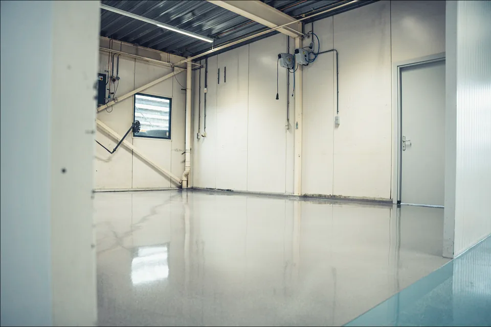 Grey epoxy coating in a commercial space with pipework and white walls