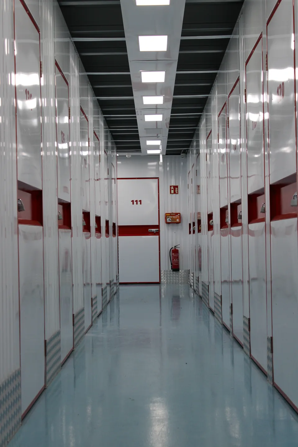 White epoxy coating in a corridor with red storage units at a self-storage facility