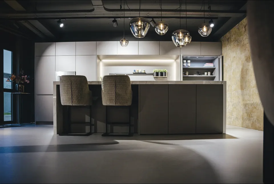 Comforpur 635 Betonlook resin floor in a kitchen showroom with a cooking island, bar stools and pendant lights