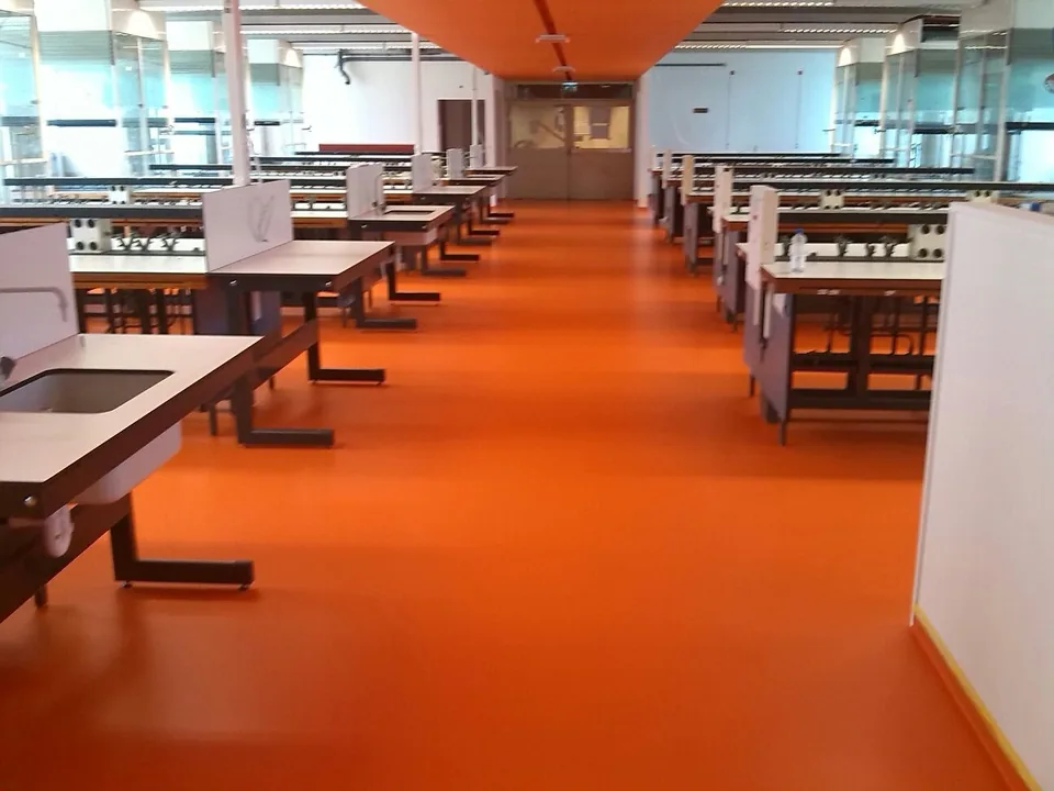 Orange resin floor in an office with work tables and green walls