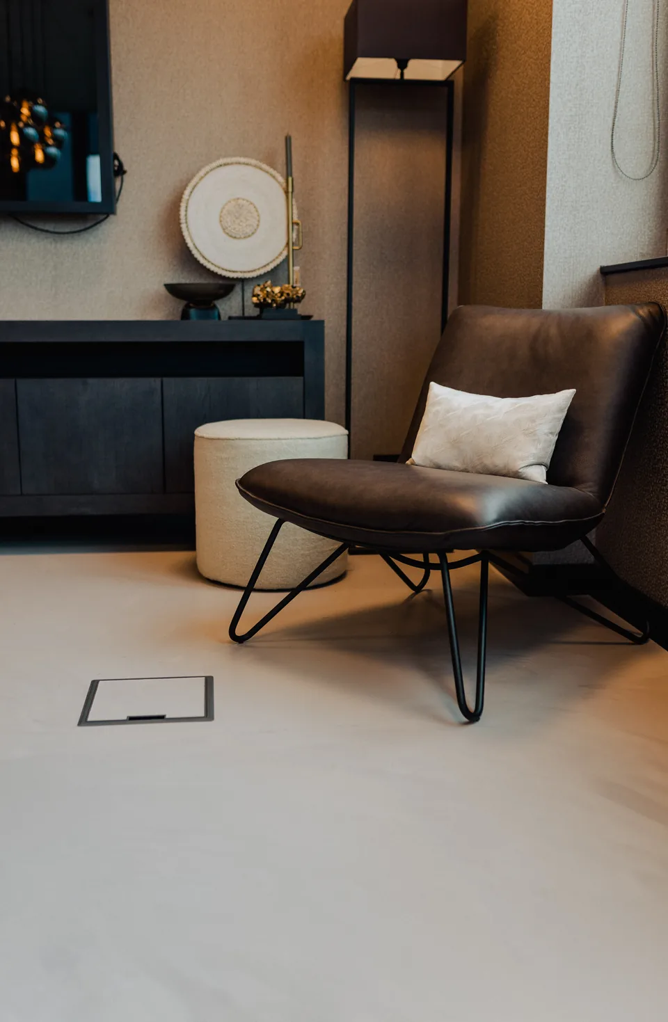 Light resin floor in a showroom beneath a leather armchair and pouffe