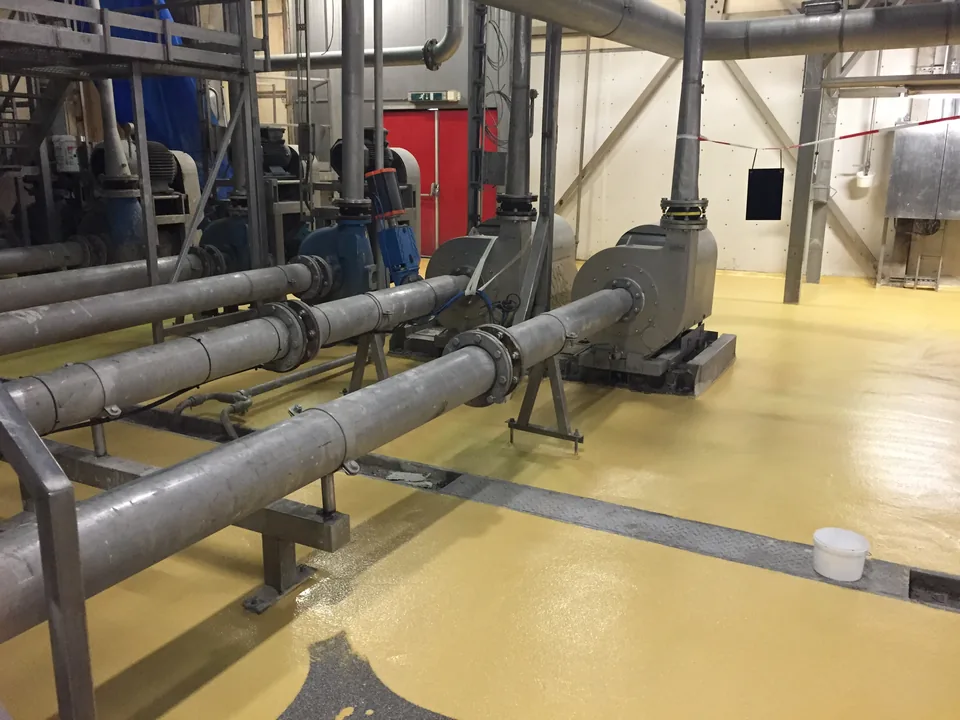 Yellow Ucrete floor in a plant room with pumps and pipework